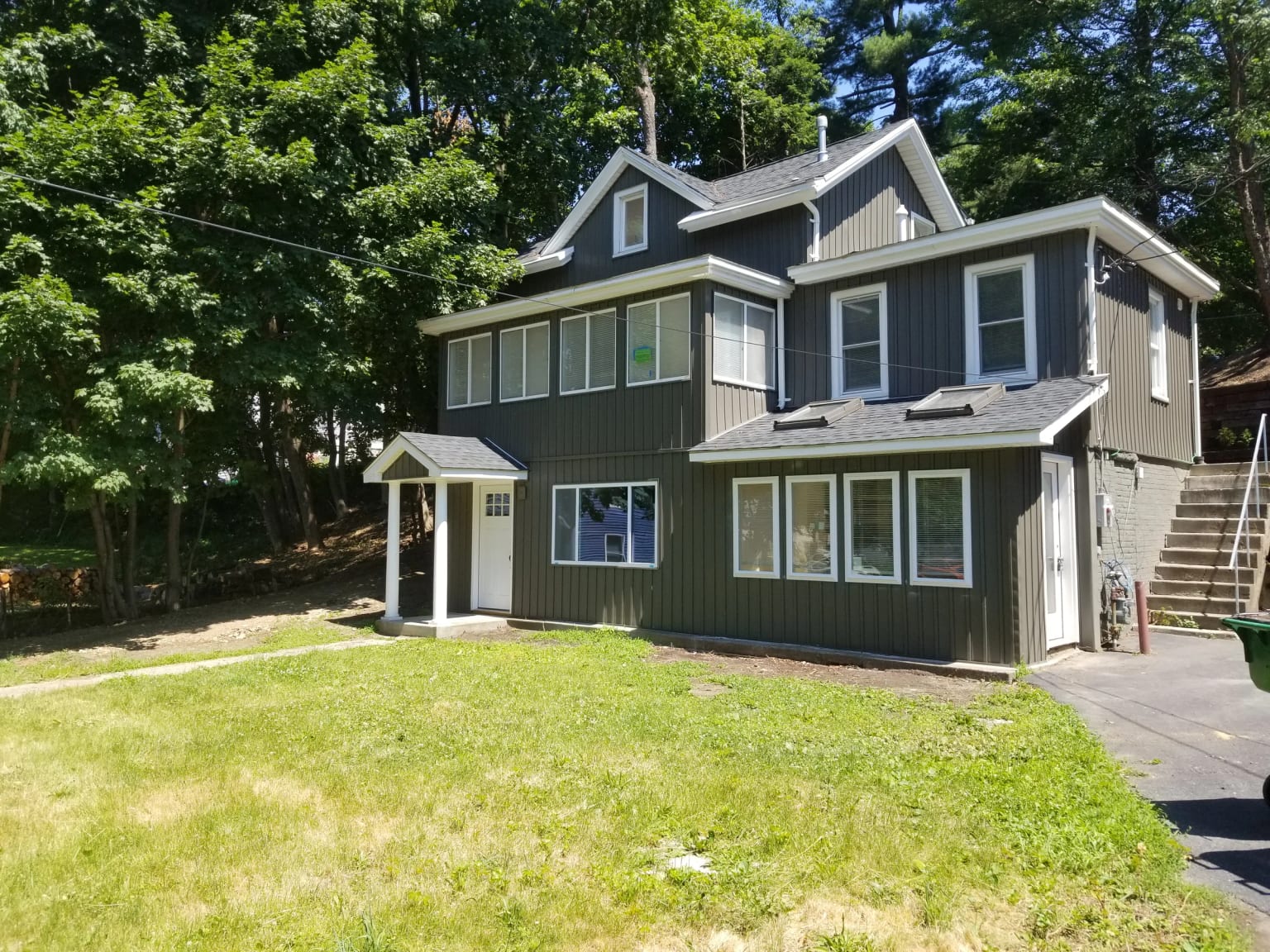 Renovated Russell Avenue house with gray vertical siding, white trim, a covered front entry, and a lawn